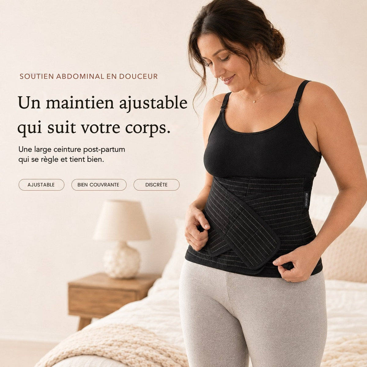 Femme portant la ceinture post-partum noire Relievoo du coffret et ajustant sa bande de maintien avant